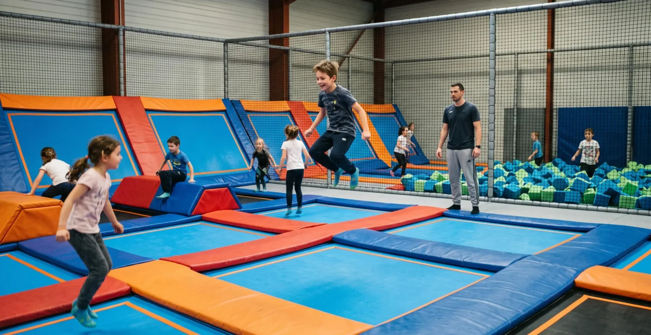 Enfants de différents âges sautant sur des trampolines interconnectés dans un trampoline park indoor avec zones de sécurité et parent superviseur